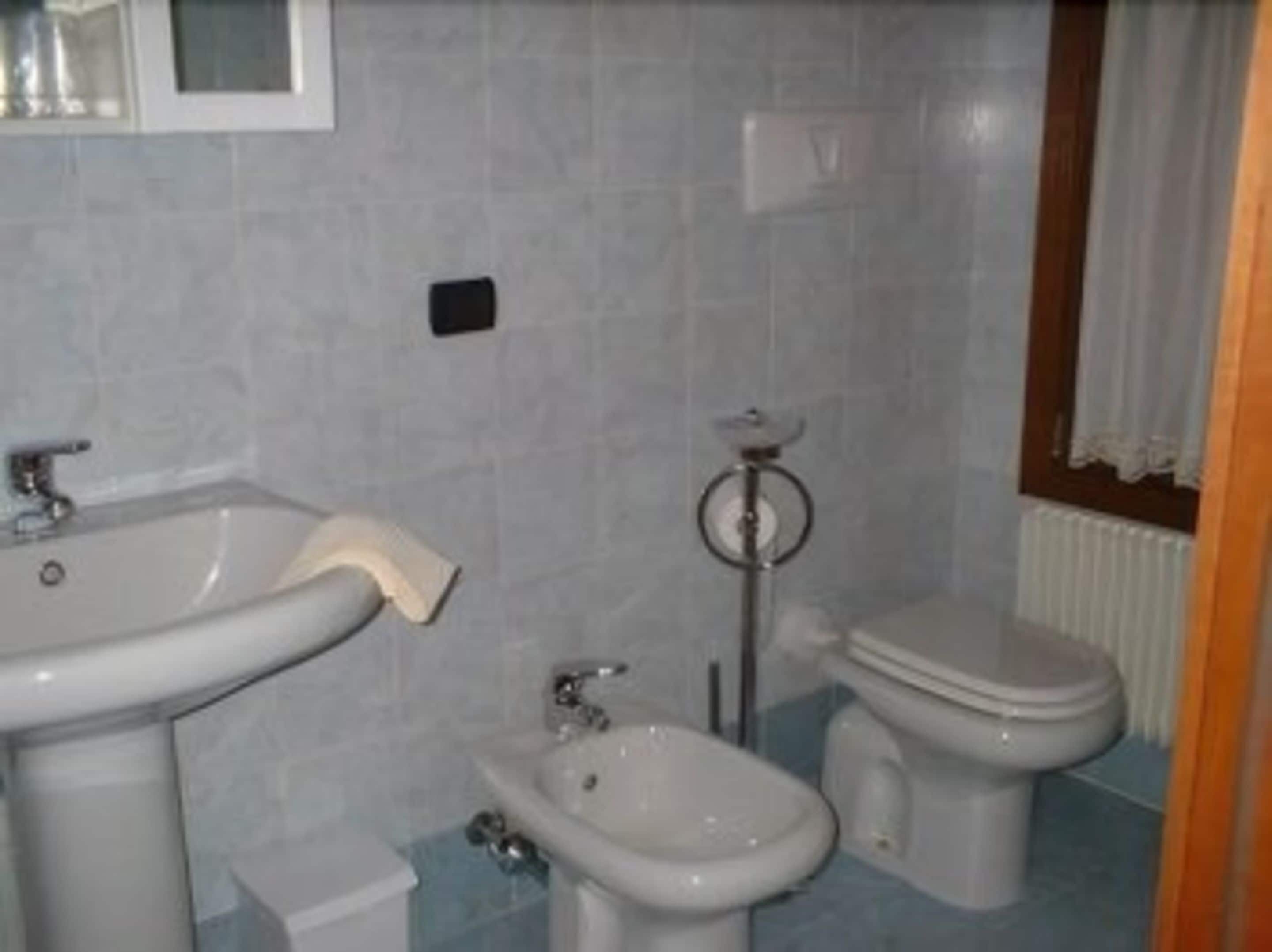 A bathroom with a sink, bidet, and toilet.