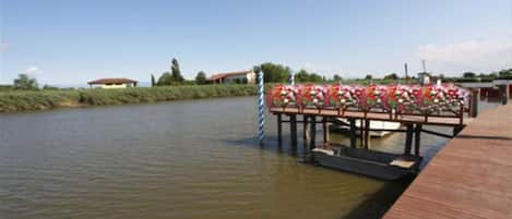 A wooden dock extending into a calm river, with a small boat docked at the end.