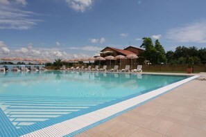 A swimming pool with lounge chairs and umbrellas, surrounded by a fence and trees. - Country House Country Club (Mestre)