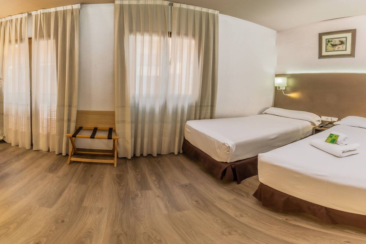 Une chambre d’hôtel équipée d’un bureau, de deux lits, d’une chaise et d’un téléviseur.