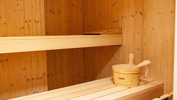 Una sauna de madera con un banco y un cubo de madera con una cuchara.