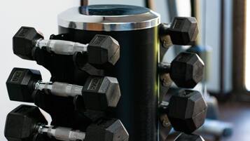 Een set zwarte halter gewichten met 2KG markeringen op een metalen cilindrische object, vermoedelijk een gewichthouder.