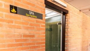 A brick wall with a sign reading "SPA Facilities" and a glass door leading to a shower area. - Hotel Pacoche Murcia (Murcia)