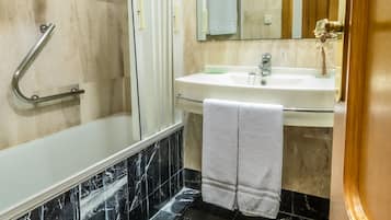 Un baño con ducha, lavamanos y espejo.