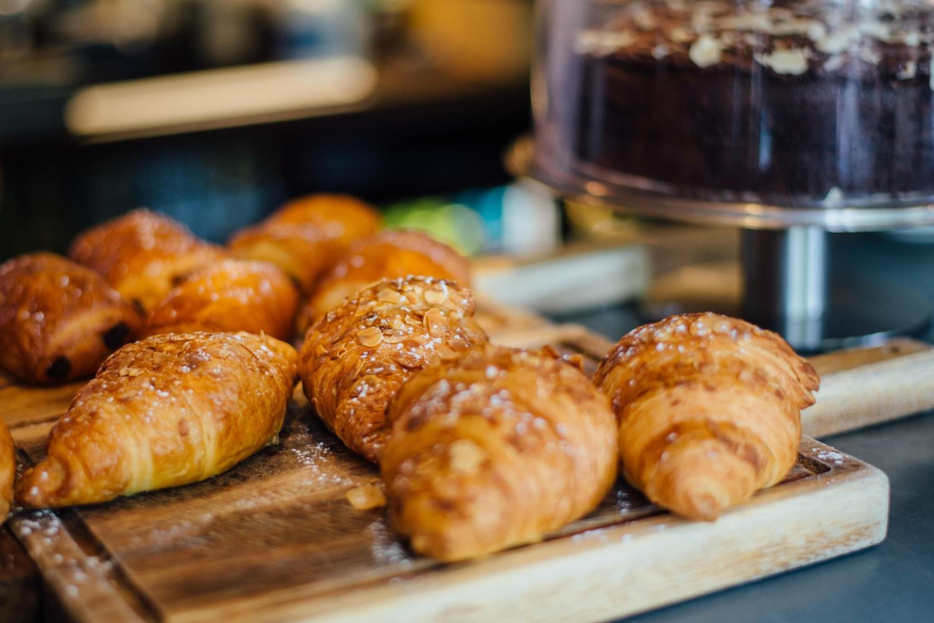 Una tabla de madera con varios pasteles dorados y color café, probablemente croissants, sobre una encimera de cocina.