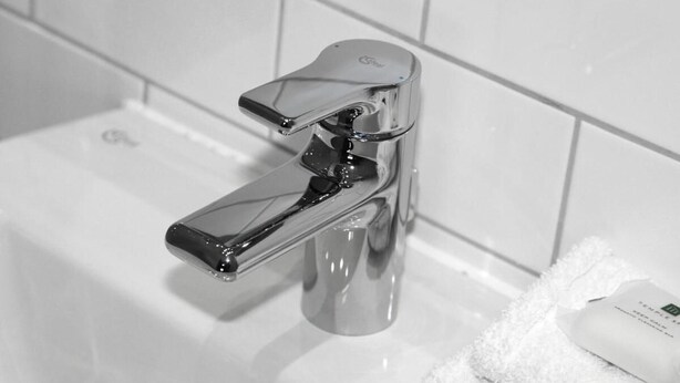 A bathroom with a chrome faucet, a white sink, and a towel with a soap dispenser. - The Kings Arms (Berkhamsted)