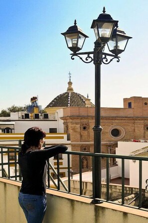 Una persona está de pie en un balcón con vistas a un edificio con una cúpula y un campanario.