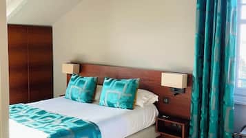 A bedroom with a bed, nightstands, a wooden headboard, and teal curtains.