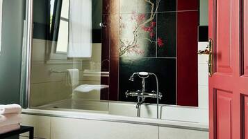 Ein modernes Badezimmer mit einer Badewanne, einer Duschkabine aus Glas und einer roten Tür.
