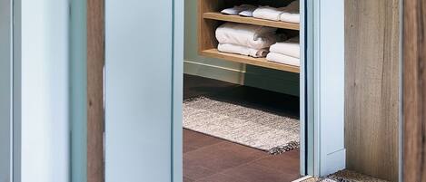A bathroom with a wooden vanity, a mirror, and neatly folded towels.