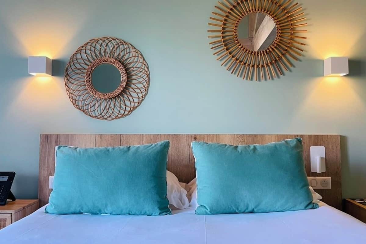 A bed with two teal pillows and a wooden headboard.
