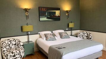 A modern hotel room with a bed, two nightstands, a chair, and a wall-mounted TV.