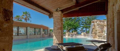A poolside area with lounge chairs and a stone structure.