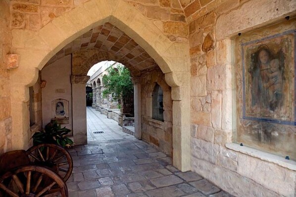 A stone corridor with an arched entrance, a wooden cart, and a painting on the wall. - Parco dei Principi Resort & SPA (Ugento)