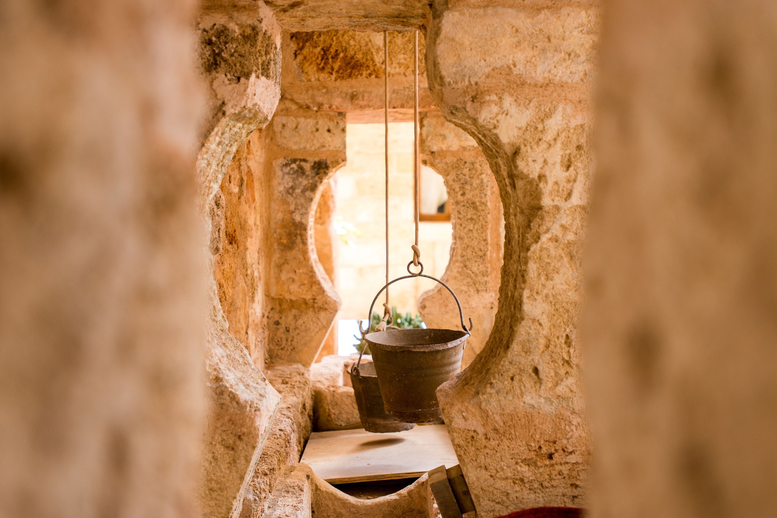 A rustic stone interior with a small table and hanging metal bucket.