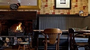 A cozy room with a fireplace, wooden furniture, and a patterned wall.
