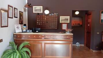 Una mesa de recepción con diplomas enmarcados, un mueble de madera y una planta en maceta.
