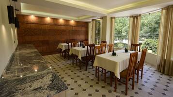 Un espace repas agrémenté de lambris en bois, de plans de travail en marbre et de tables dressées pour le service.