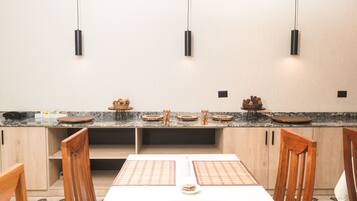 A modern kitchen with a marble countertop, wooden cabinets, and pendant lighting.