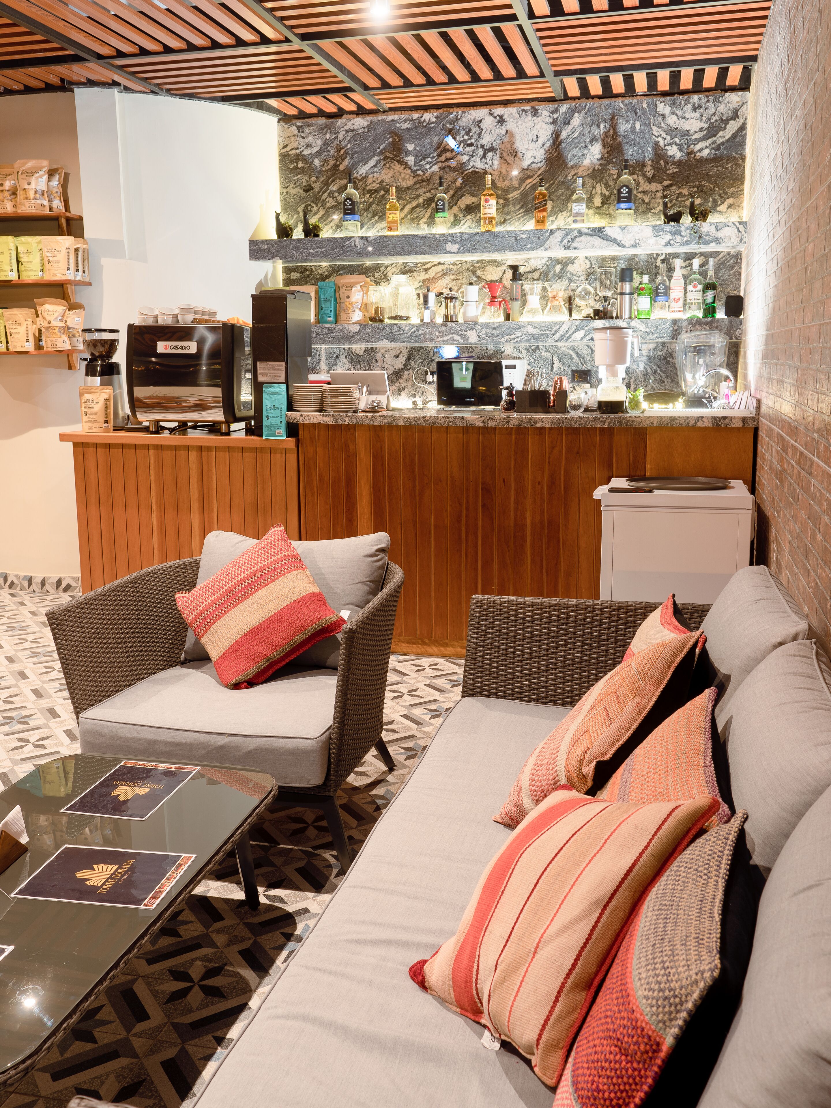 A cozy seating area with wicker furniture and a coffee machine.