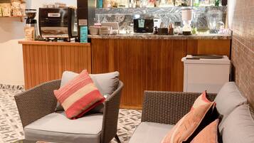 A cozy seating area with wicker furniture and a coffee machine.