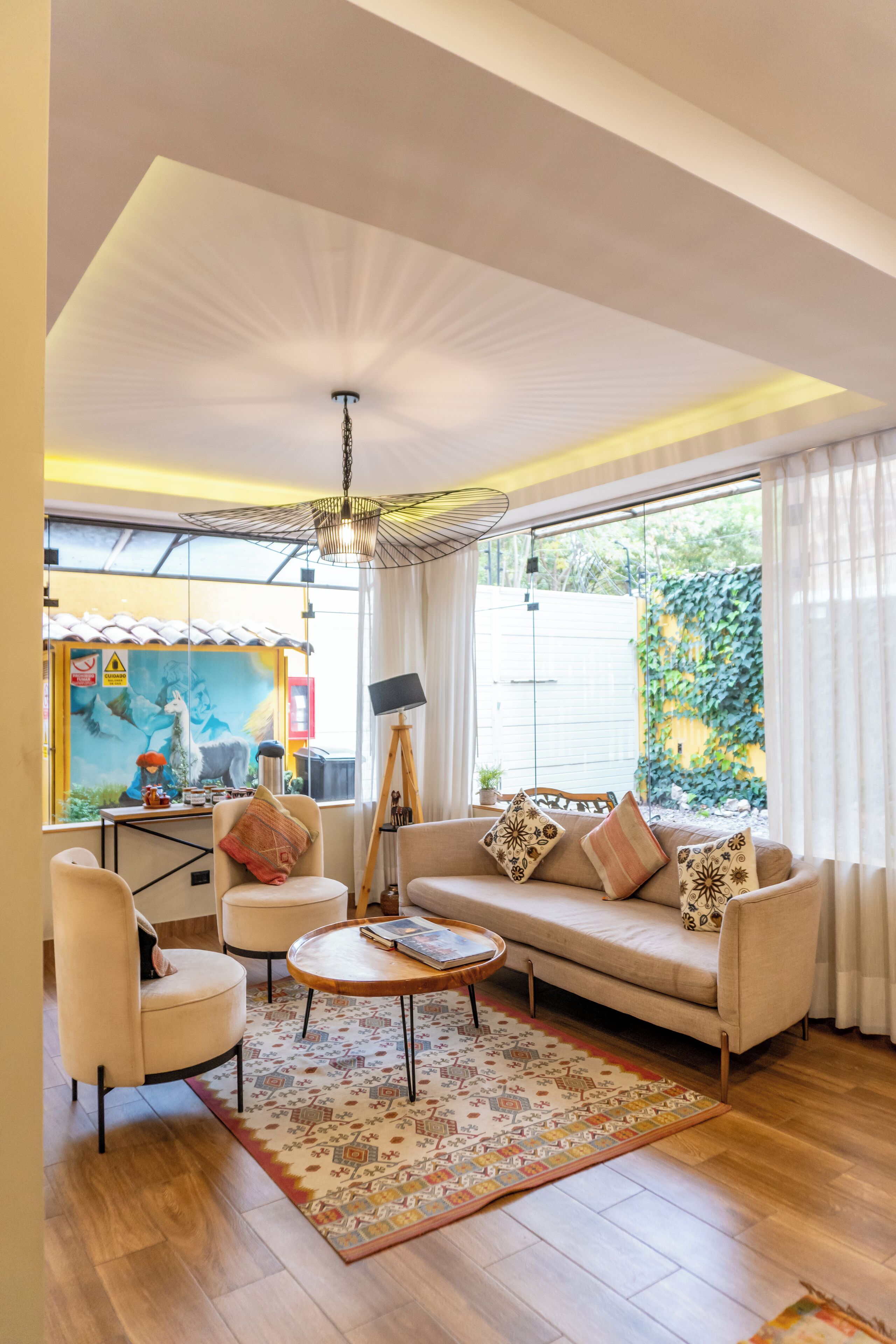 A modern living room with a sofa, armchairs, a coffee table, and a large window with curtains.