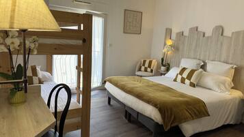 A bedroom with a bunk bed, a bedside table with a lamp, a chair, and a bed with pillows.