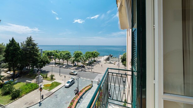 A balcony with a view of a coastal street, trees, and a clear sky. - Bed & Breakfast Relais San Giacomo (Maiori)
