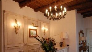 A room with a wooden ceiling, a chandelier, a white cabinet with a vase of flowers, and wall-mounted sconces. - Bed & Breakfast Relais San Giacomo (Maiori)