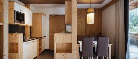 A modern kitchen with wooden cabinets, a built-in microwave, and a dining area with a table and chairs.