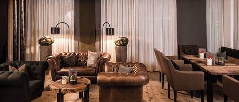 A cozy lounge area with leather sofas, a wooden coffee table, and a dining table with chairs.