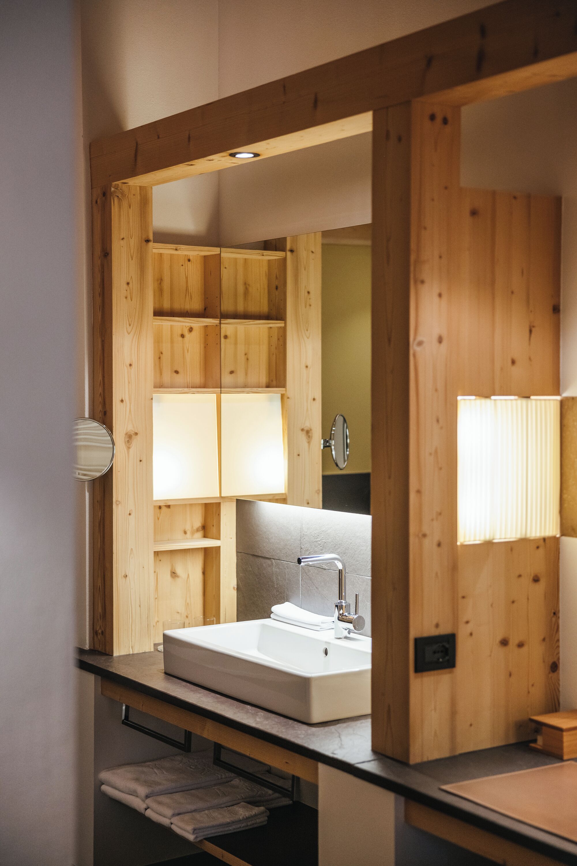 Une salle de bain avec une structure en bois, dotée d’un lavabo et d’un miroir encastrés.
