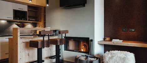 Una cocina moderna con armarios de madera, horno empotrado y un televisor grande sobre la chimenea.