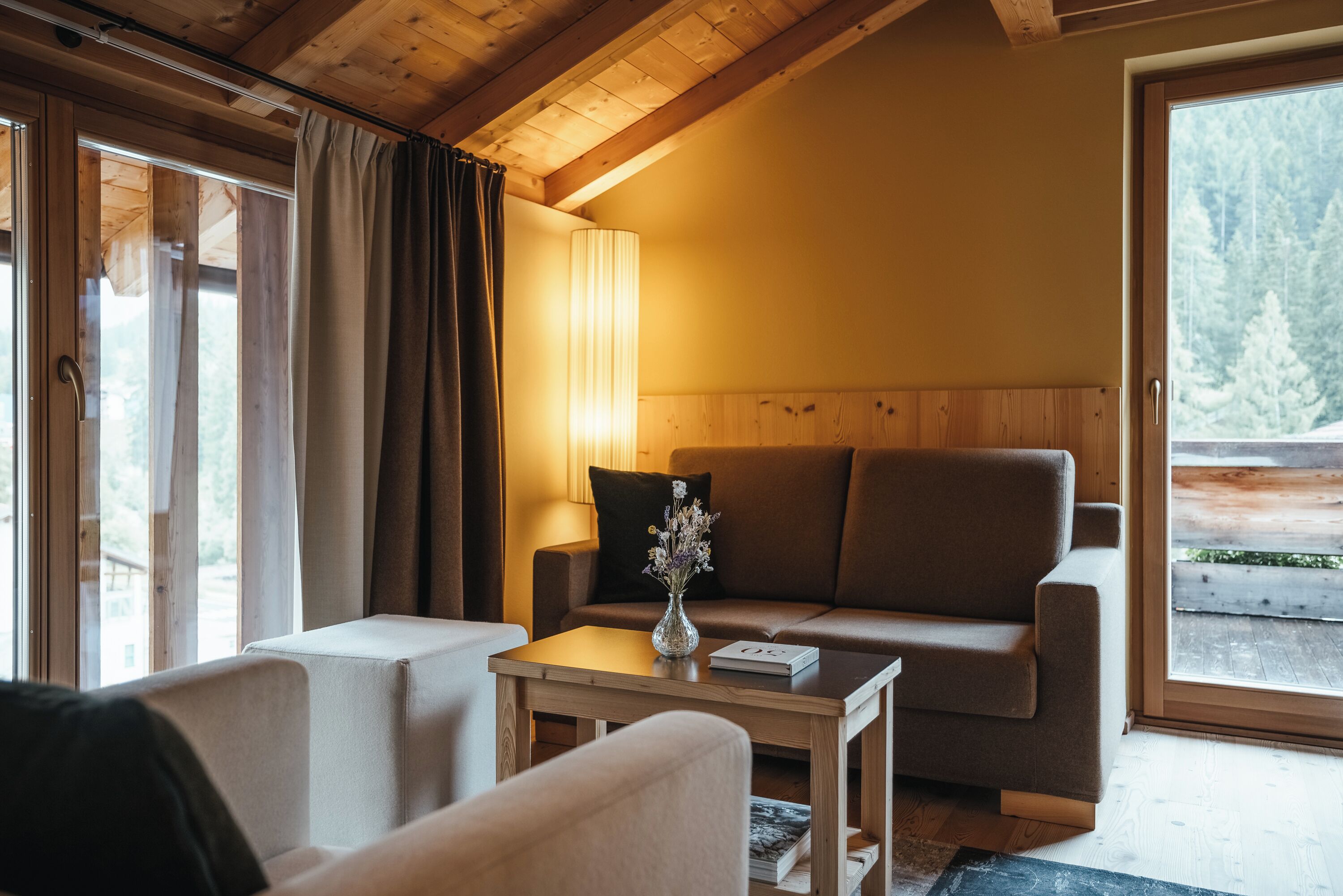 Una sala acogedora con un sofá, una mesa de centro y un jarrón de flores.