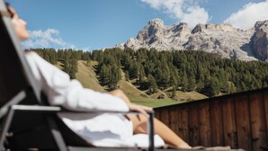 Una persona reclinada en una silla con vista a la montaña.