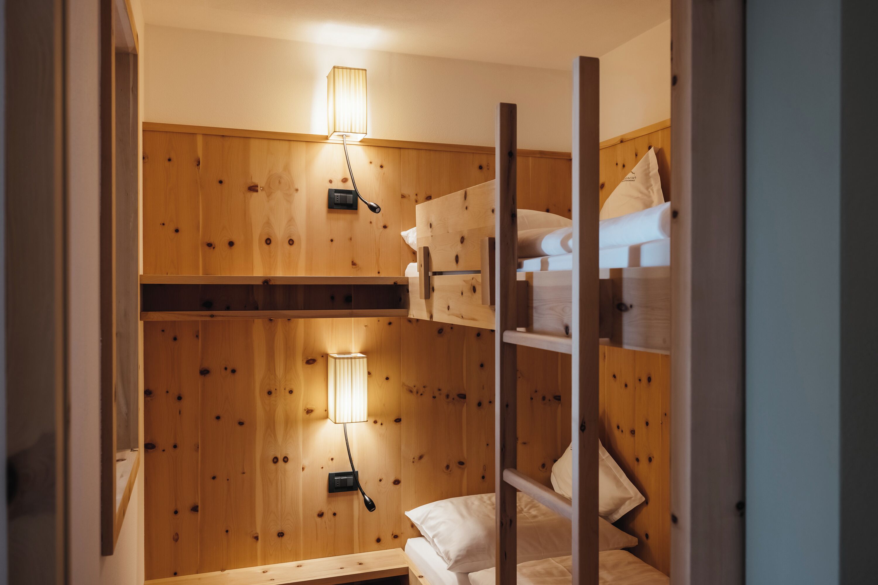 Ein Schlafraum mit Etagenbetten, Holzwänden und zwei Nachttischlampen.