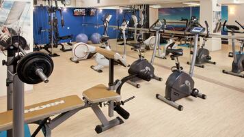 A gym with various exercise equipment, including treadmills, stationary bikes, and weight machines.