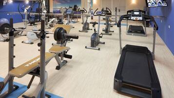 A gym with various exercise equipment, including treadmills, weight machines, and a bench press.
