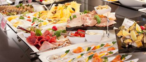 A buffet with various food items including meats, cheeses, and seafood.