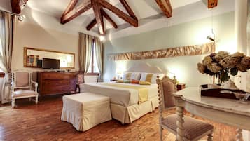 A bedroom with a large bed, a dresser, a television, and a dining table.