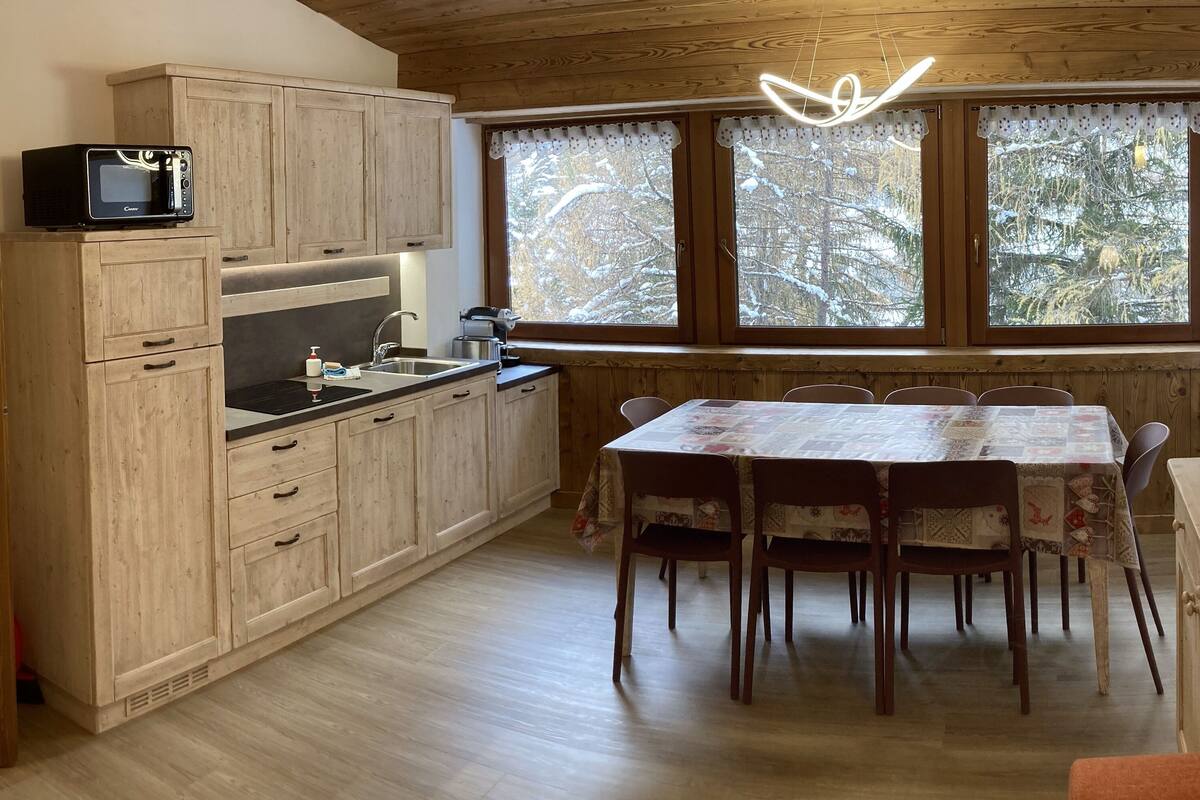 Une cuisine avec des meubles de rangement en bois, un four à micro-ondes, un évier et une table à manger avec des chaises.