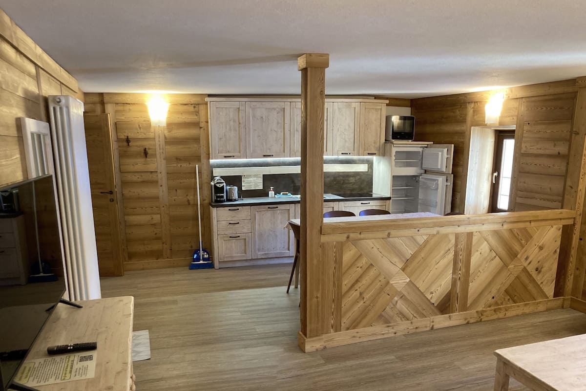 Un intérieur rustique en bois, avec un coin cuisine, un plancher en bois et une table à manger.