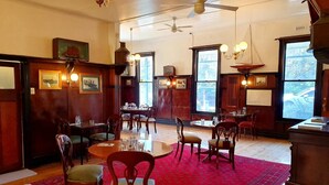 A dining area with wooden furniture, a red carpet, and large windows. - Point Lonsdale Guest House (Point Lonsdale)