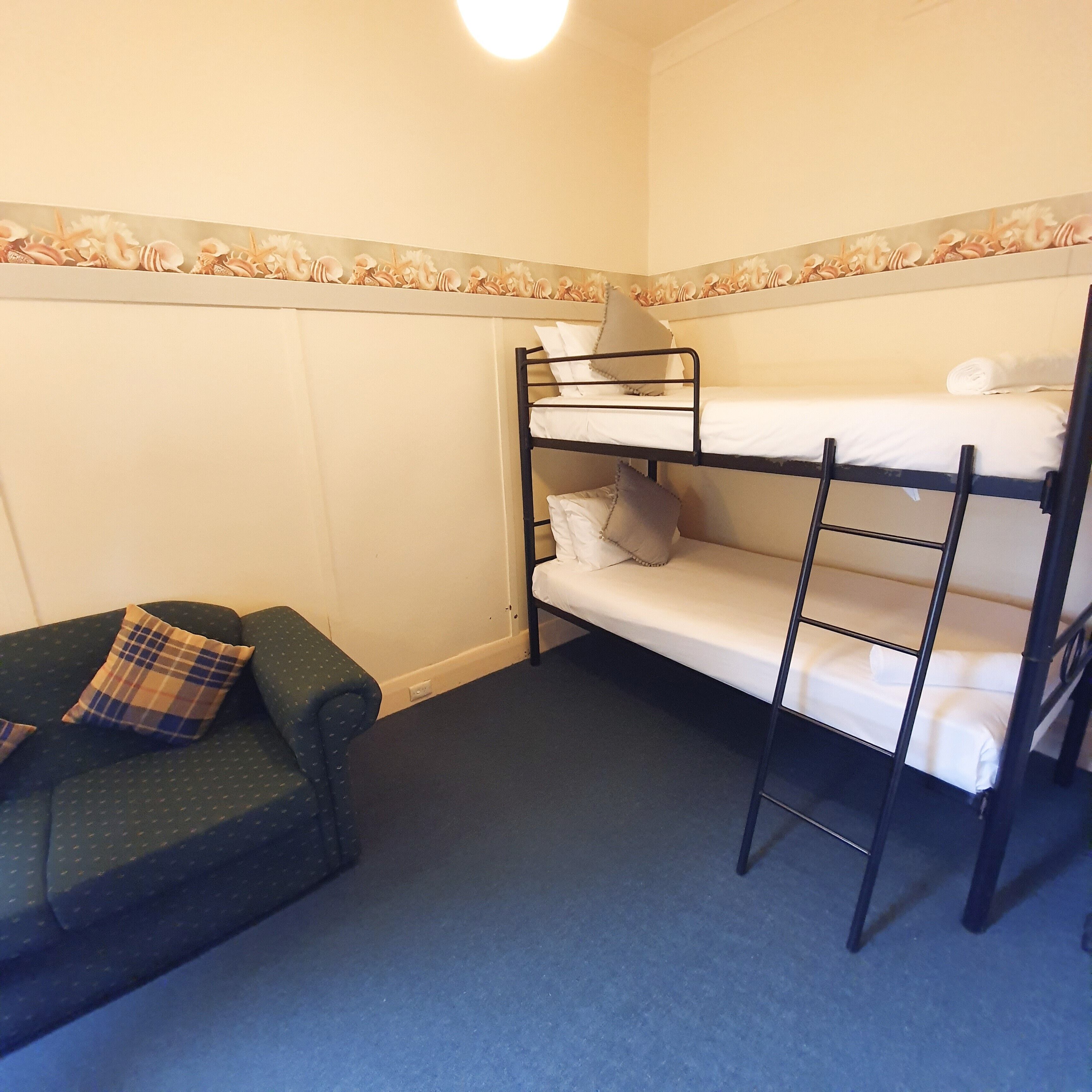 Een slaapkamer met een stapelbed, een groene bank en een kussen met een patroon.