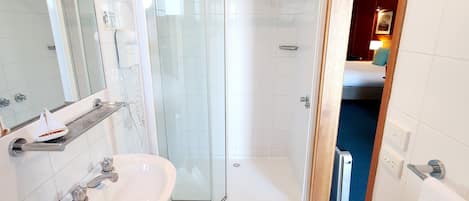 A modern bathroom with a glass-enclosed shower, a white sink, and a mirror.