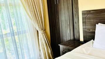 Quarto com cama, guarda-roupa de madeira e janela com cortinas.