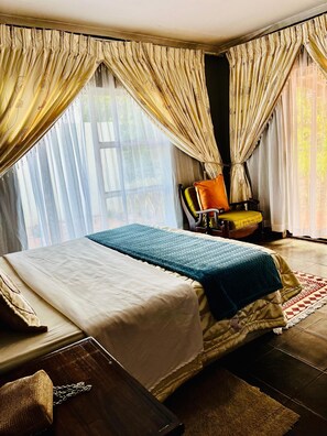 A hotel room with a bed, a chair, and a table. - Copacopa Lodge and Conference Centre (Thulamela)