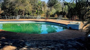A swimming pool surrounded by lounge chairs and a brick deck. - Copacopa Lodge and Conference Centre (Thulamela)