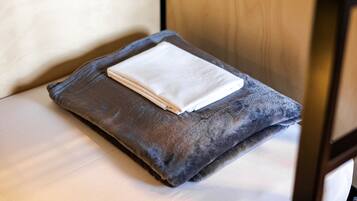A neatly folded white towel on a dark gray pillow in a room with wooden furniture.