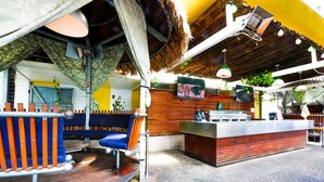 A restaurant with a wooden deck, a bar area, and a thatched roof. - Bunk Backpackers (Fortitude Valley)